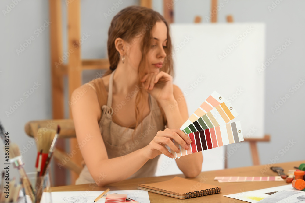 Female artist with paint color palettes in workshop