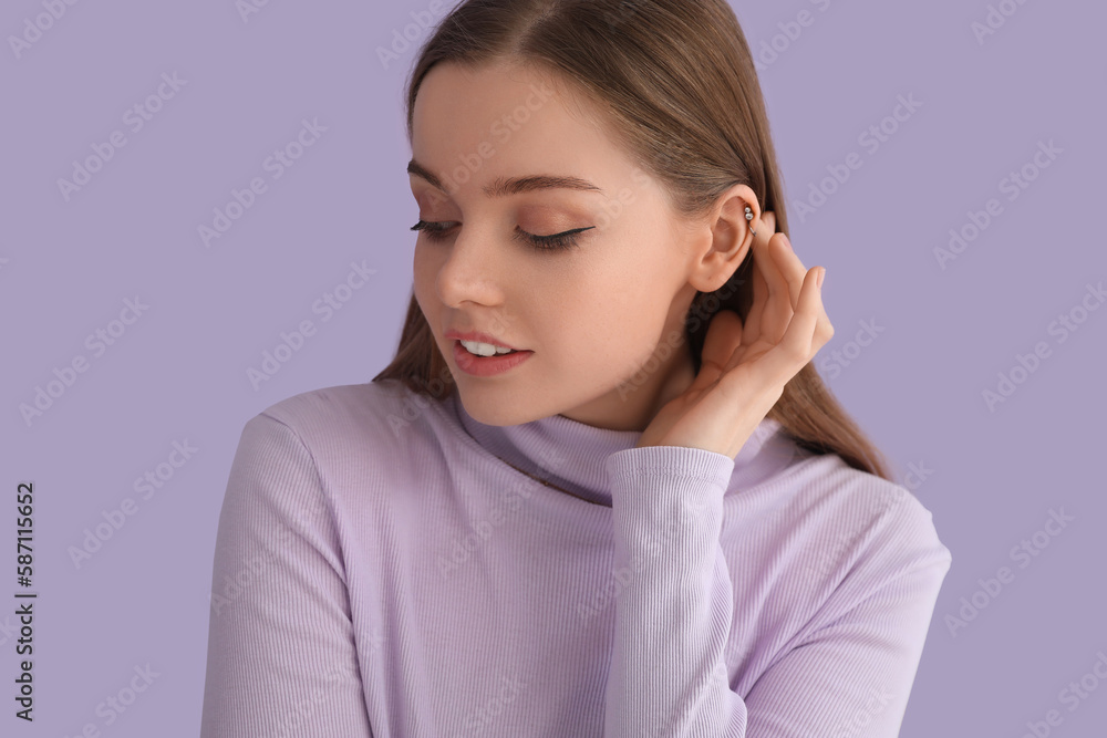 Young woman in sweater touching hair on lilac background, closeup