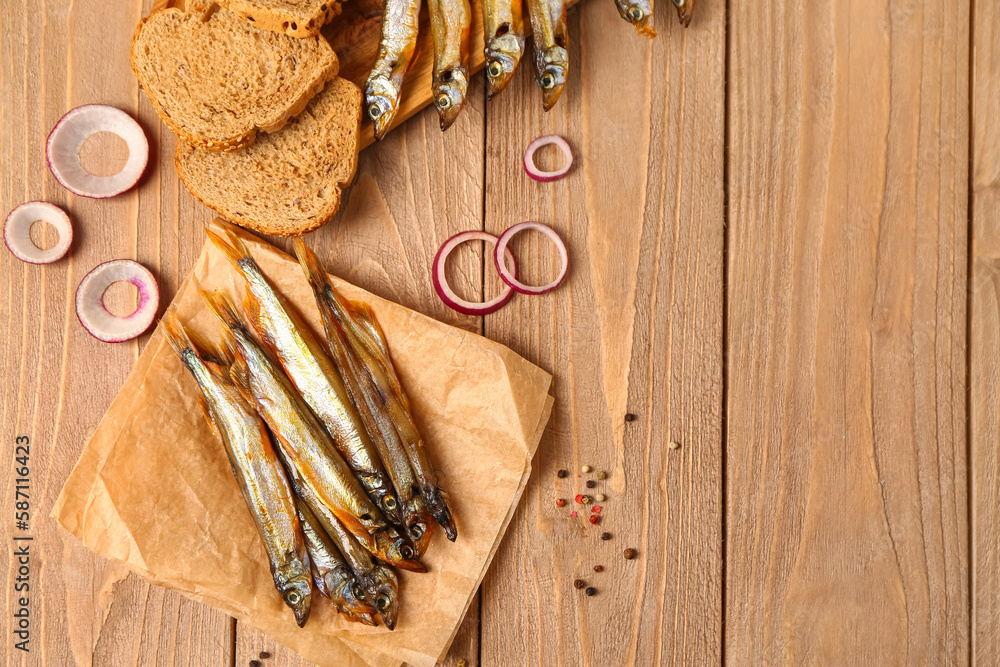 Parchment with delicious smoked capelin on wooden background