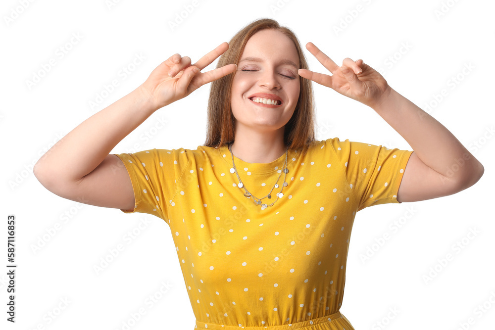 Beautiful redhead woman in yellow dress showing victory gesture on white background