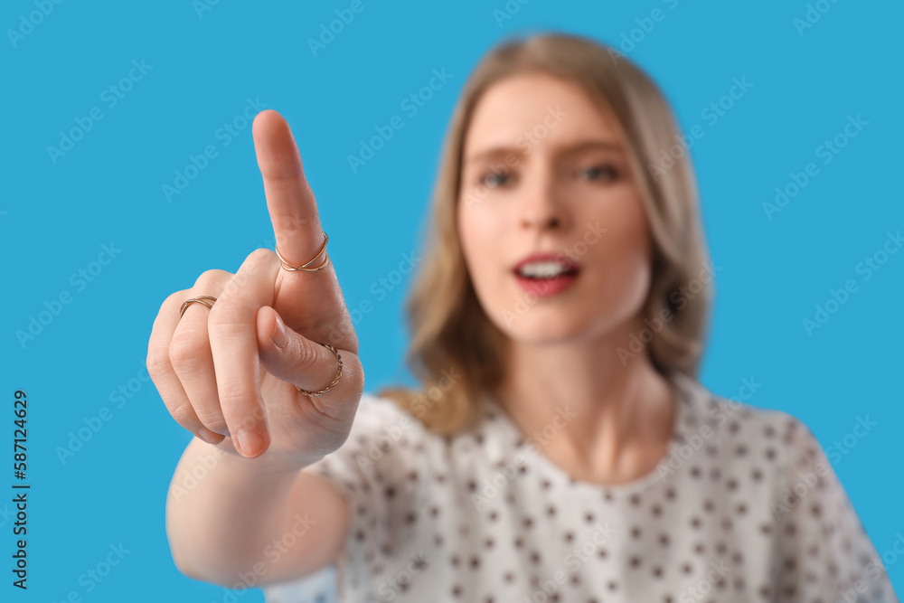 Young woman using virtual screen on blue background, closeup