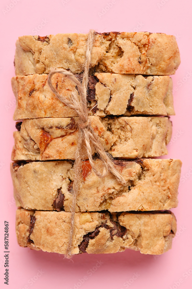 Delicious biscotti cookies tied with thread on pink background