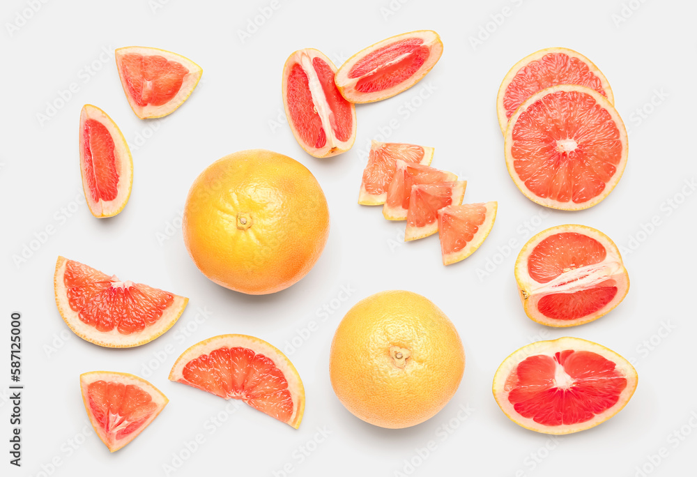 Composition with cut and whole ripe grapefruits on white background