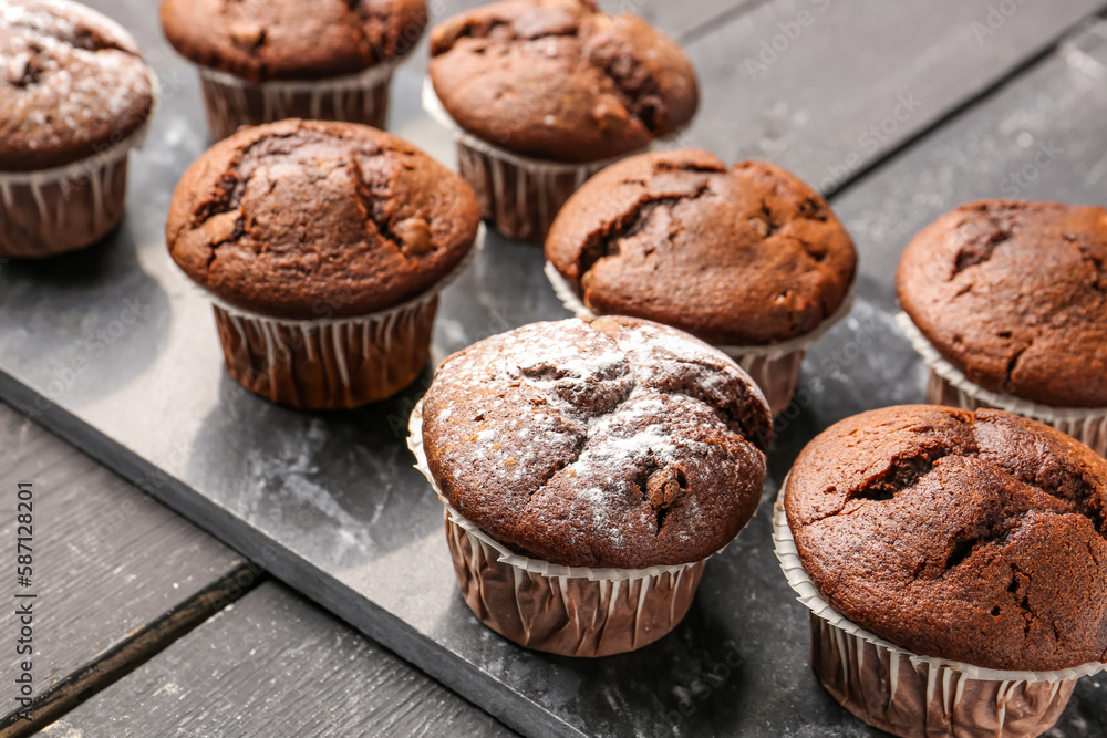 Board with tasty chocolate cupcakes on dark wooden background