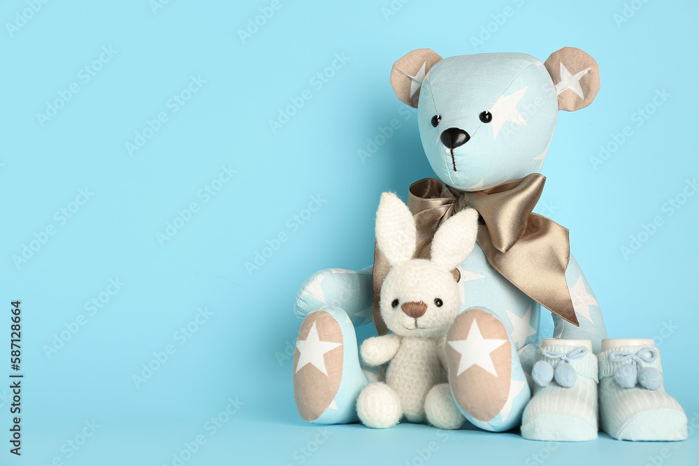 Toy bear and bunny with baby socks on blue background