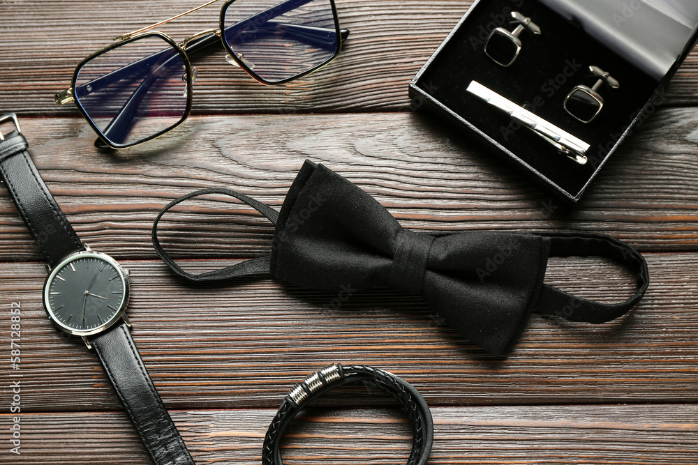 Set of stylish male accessories with bow tie on wooden background