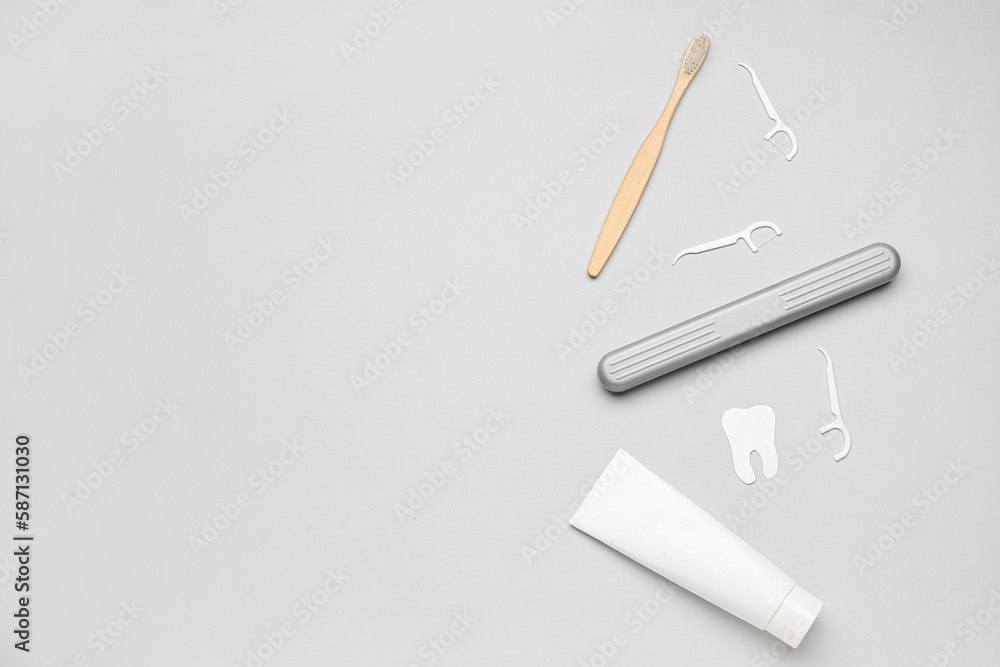 Floss toothpicks, tube of paste, brush and tooth model on grey background