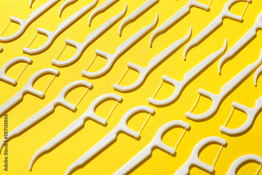 Many floss toothpicks on yellow background