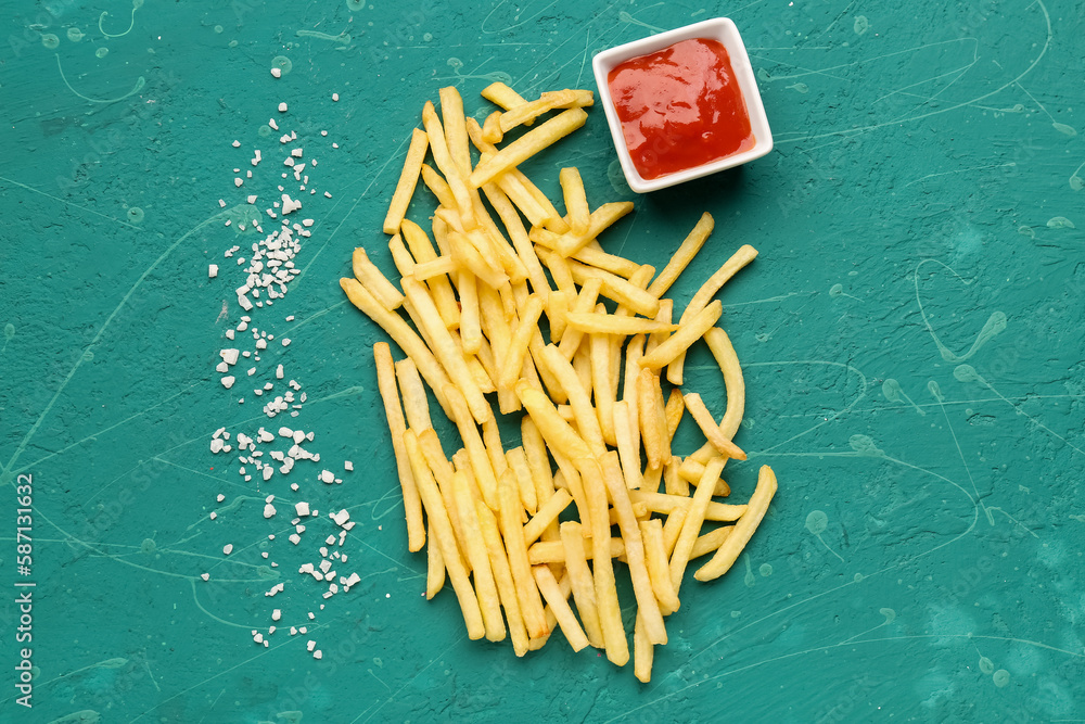 Tasty french fries, salt and ketchup on green background