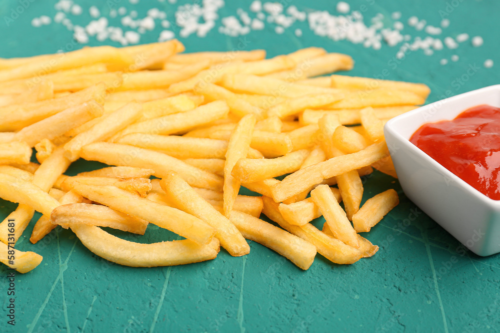 Tasty french fries, salt and ketchup on green background