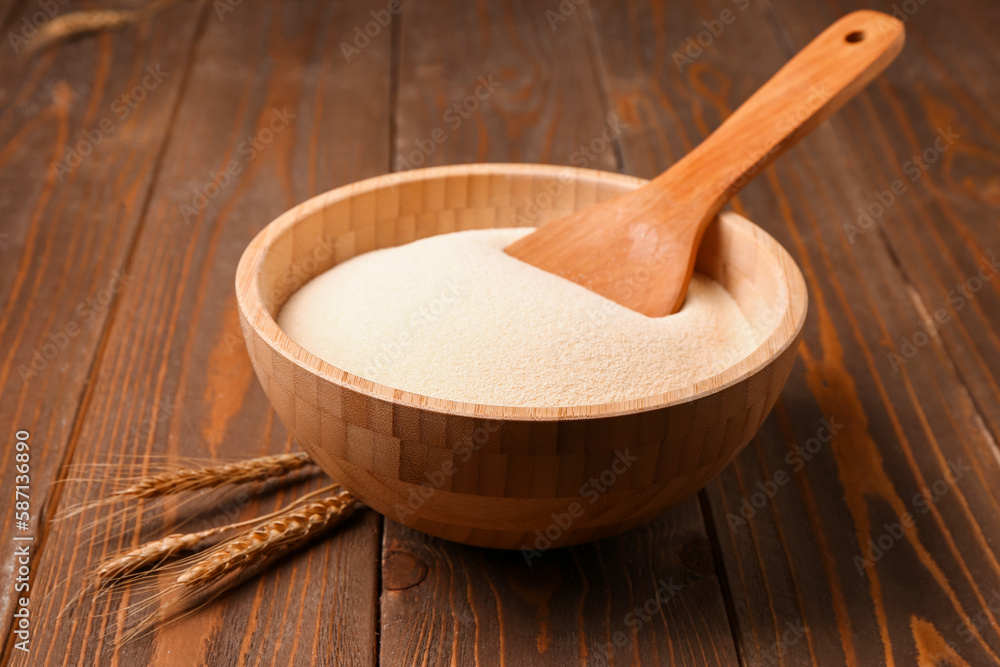 Bowl with raw semolina on wooden background