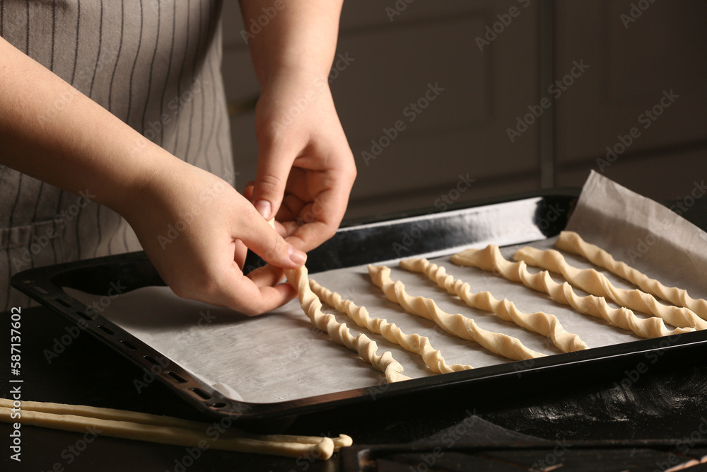 Woman preparing Italian Grissini at table in kitchen, closeup