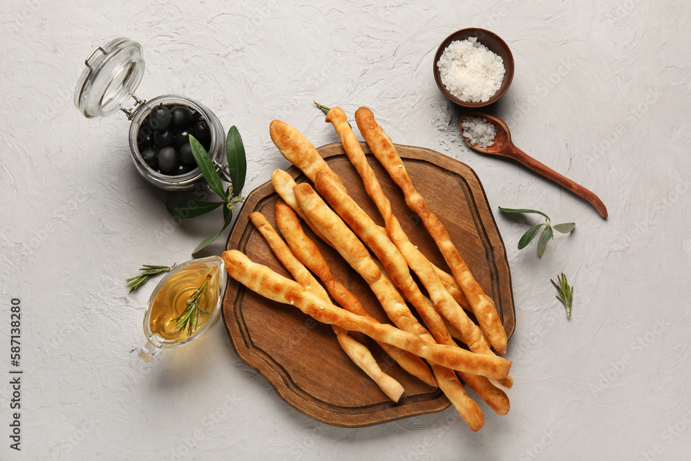 Wooden board with tasty Italian Grissini on light background