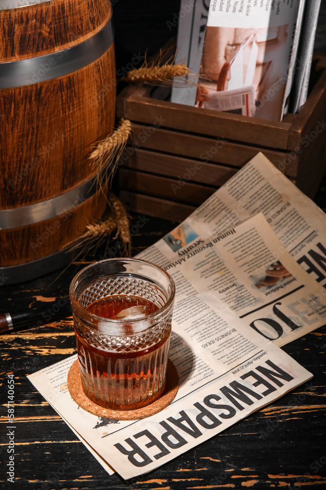 Glass of cold rum with newspaper on dark wooden background