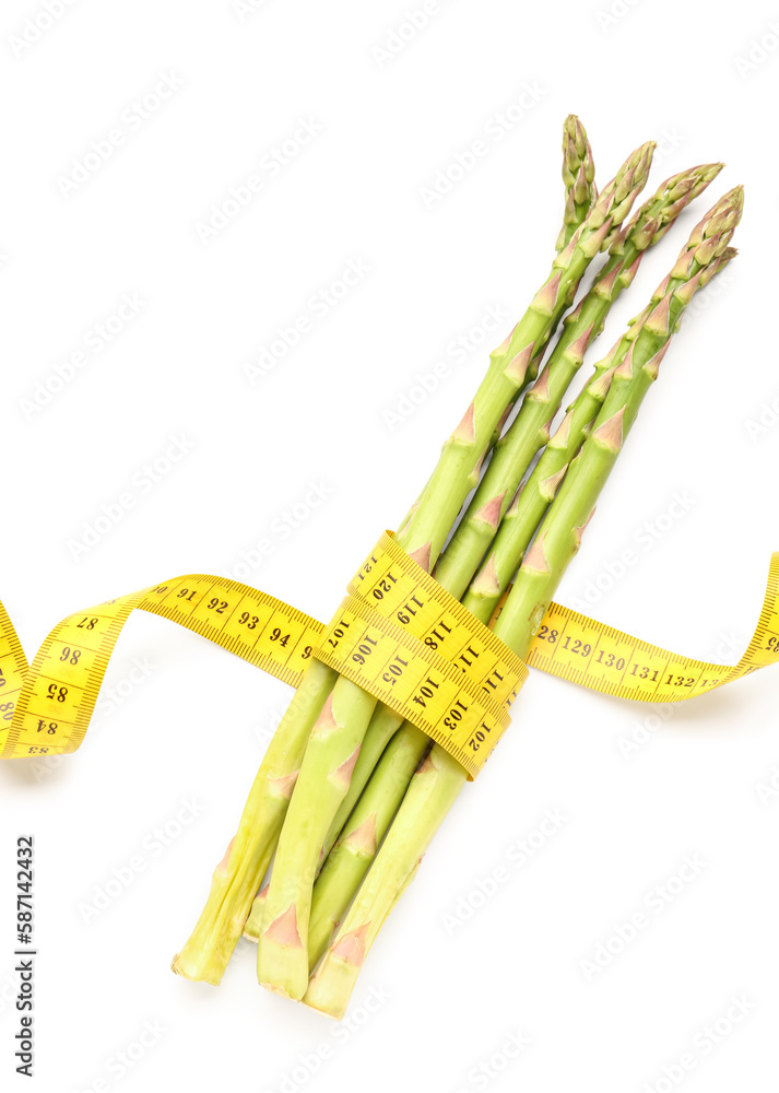 Asparagus and yellow measuring tape on white background. Diet concept