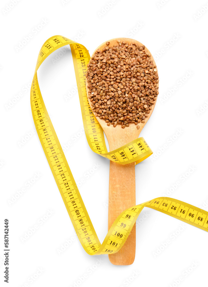 Wooden spoon with buckwheat and yellow measuring tape on white background. Diet concept