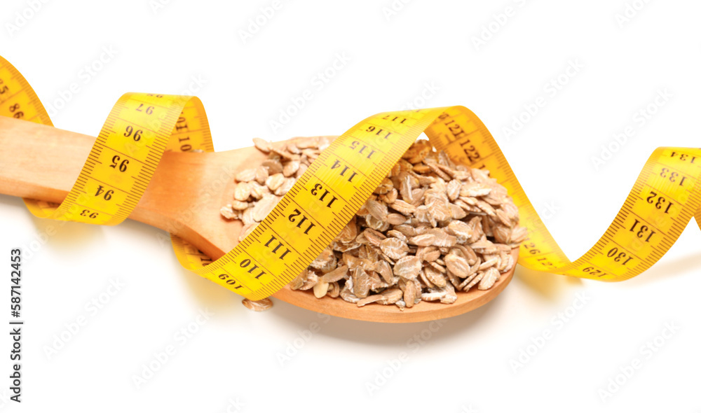 Wooden spoon with oat flakes and yellow measuring tape on white background. Diet concept