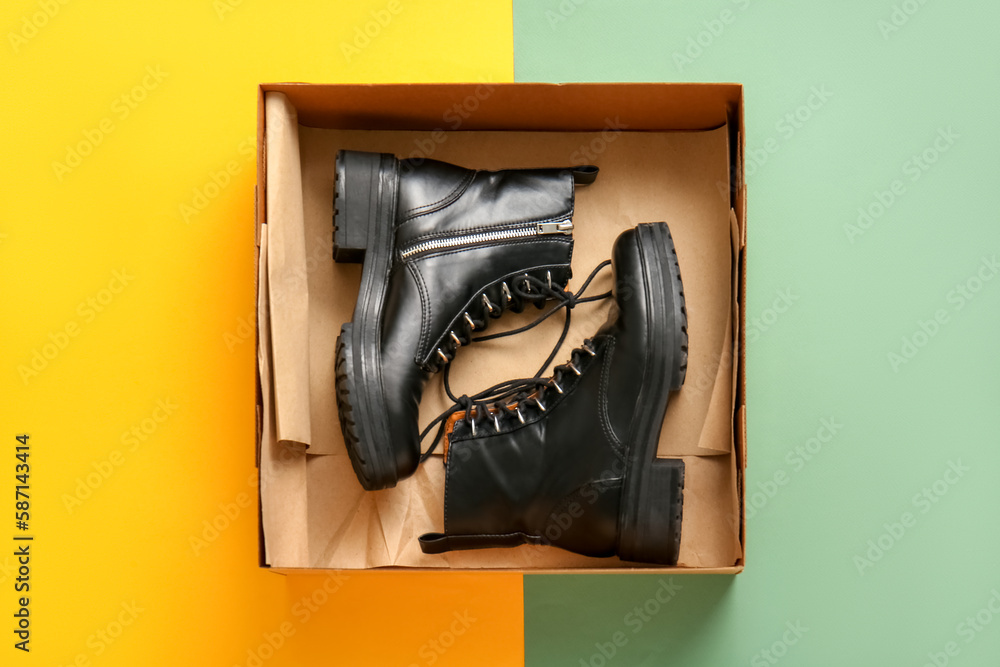 Cardboard box with stylish shoes on color background