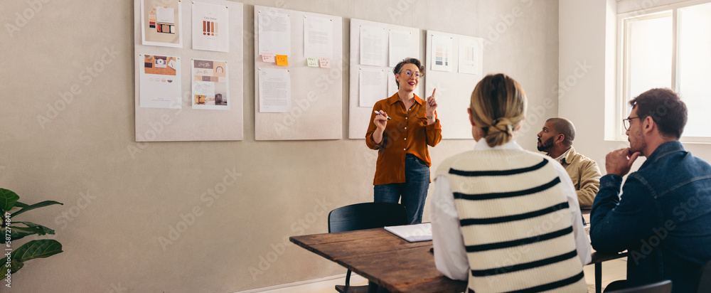 Mature designer pitching her idea to her team in a creative office