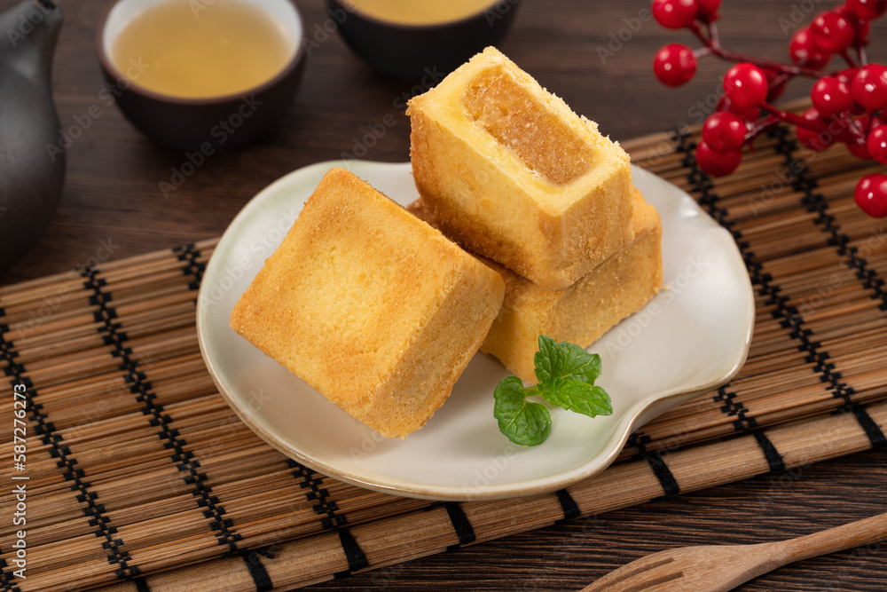 Delicious pineapple cake pastry in a plate on wooden table background with tea.