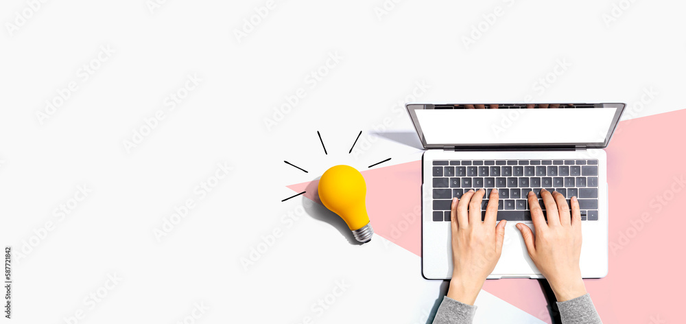 Person using a laptop computer and a light bulb - Flat lay