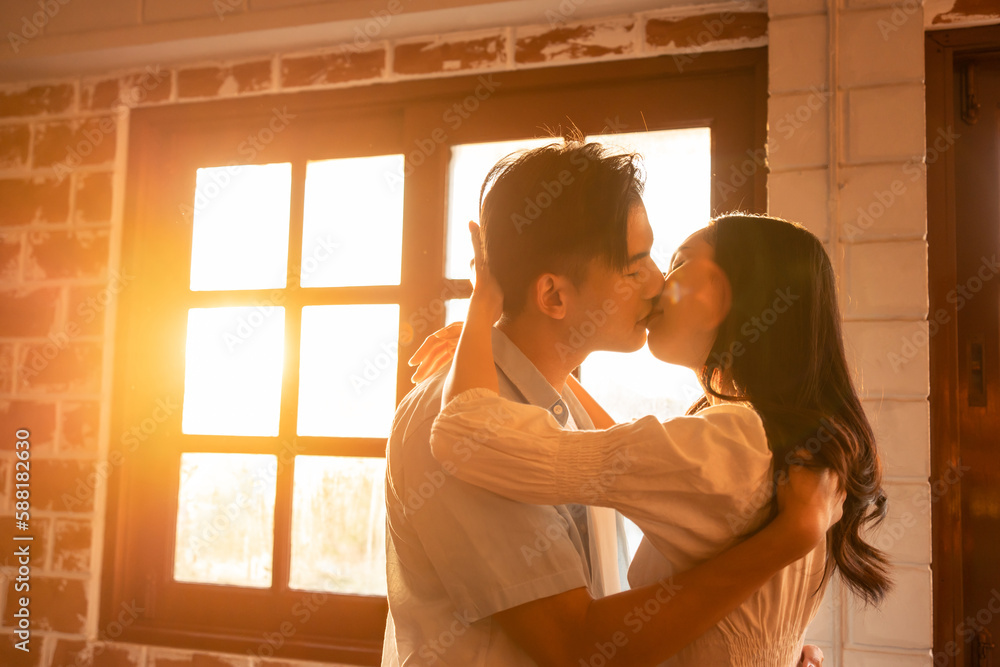 Asian young man and woman kissing each other in living room at home. 