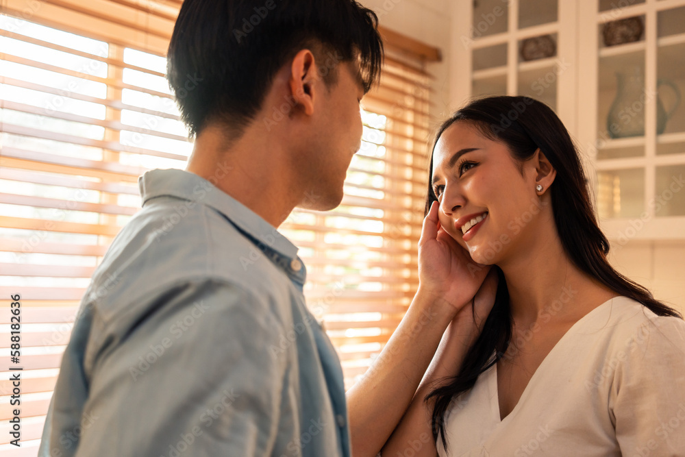 Asian young man and woman looking each other in living room at home. 