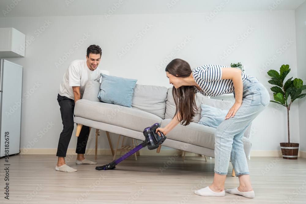 Caucasian young man and woman cleaning living room together at home.