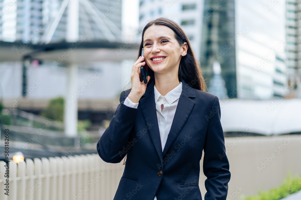 Caucasian young businesswoman talking on smartphone while walk in city. 