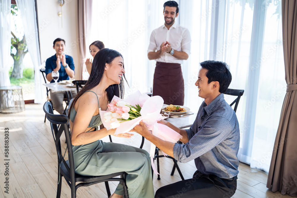 Asian romantic man making surprise proposal of marriage to girlfriend. 