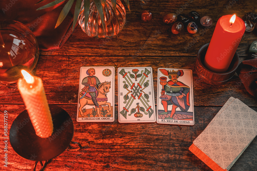 Reading a future by tarot cards on rustic wooden table. Three tarot cards from Marseille Tarot deck 