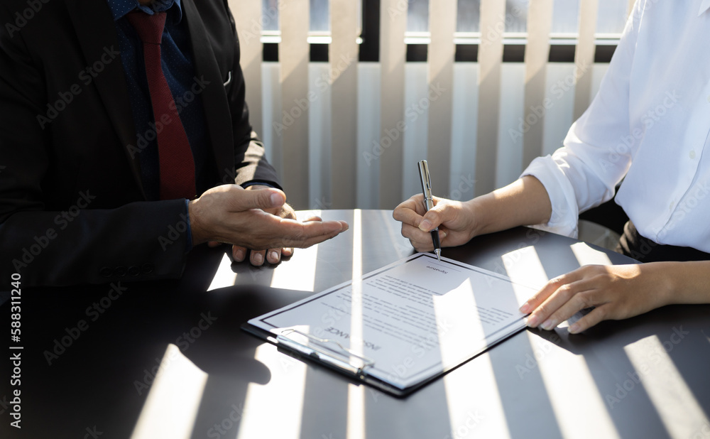 Businessman in suit in his office showing an insurance policy and pointing with a pen where the poli