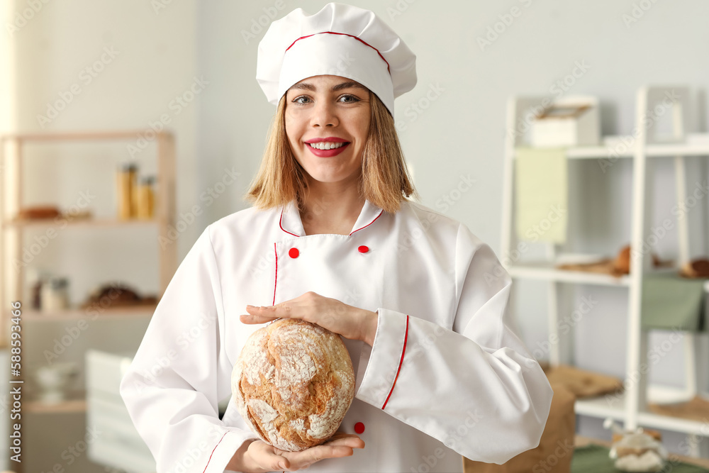 Female baker with fresh bread in kitchen