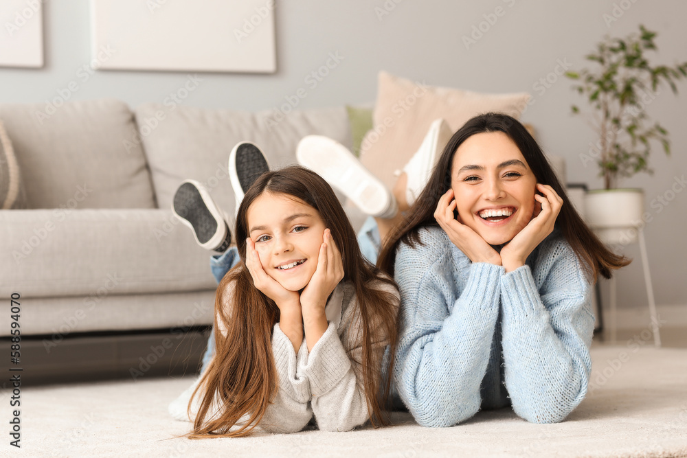 Little girl and her mother in knitted sweaters lying on floor at home