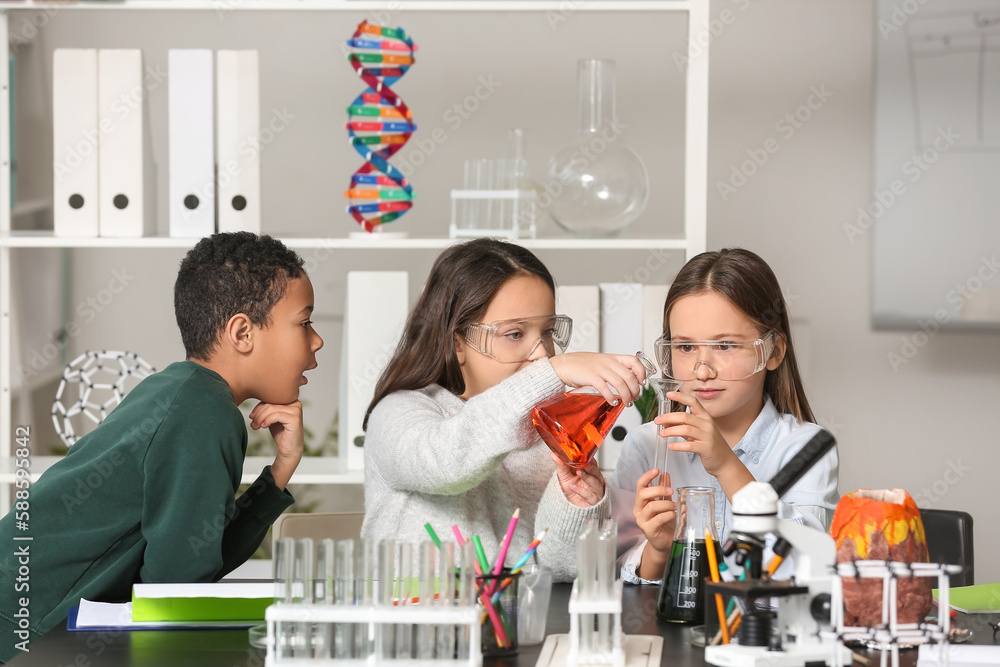 Little children conducting chemistry experiment in science classroom