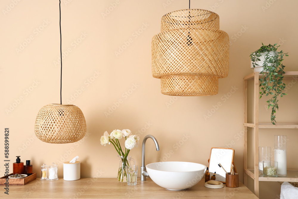 Sink, vase with flowers and bath accessories on table in bathroom