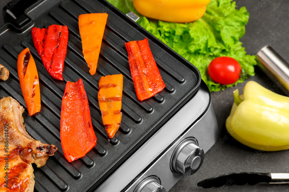 Modern electric grill with tasty vegetables on dark background, closeup