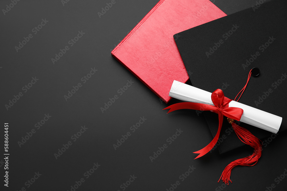 Diploma with red ribbon, graduation hat and book on black background