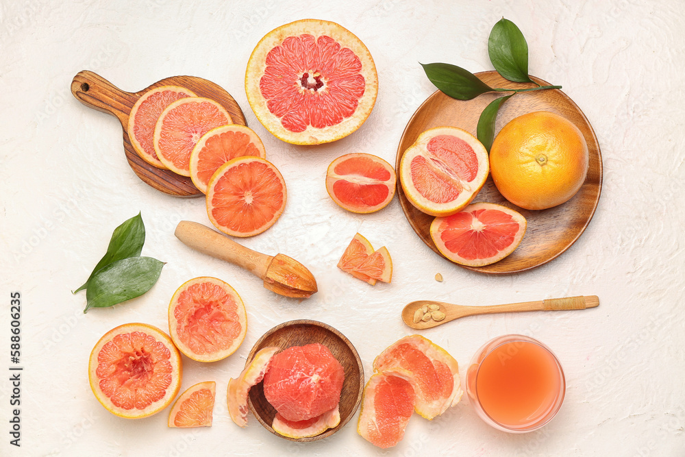 Composition with cut ripe grapefruits and glass of juice on light background