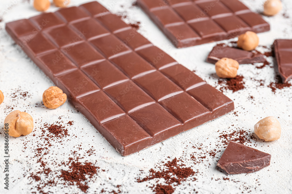 Tasty chocolate, hazelnuts and coffee powder on light background, closeup