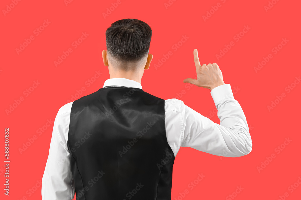 Handsome man showing loser gesture on red background, back view