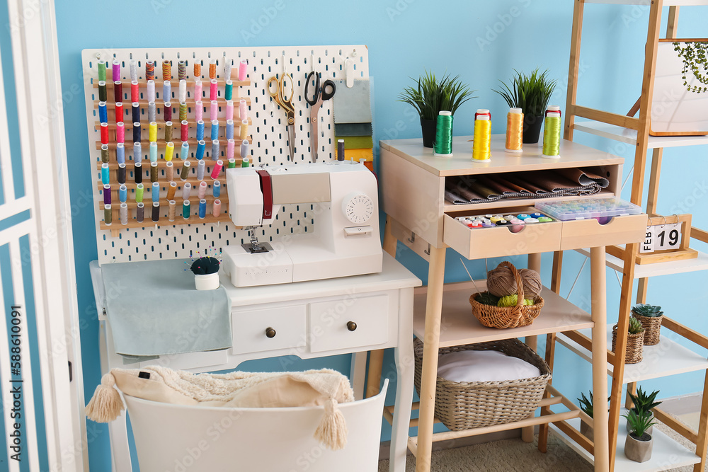 Tailors workplace with sewing machine, pegboard and thread spools in modern atelier