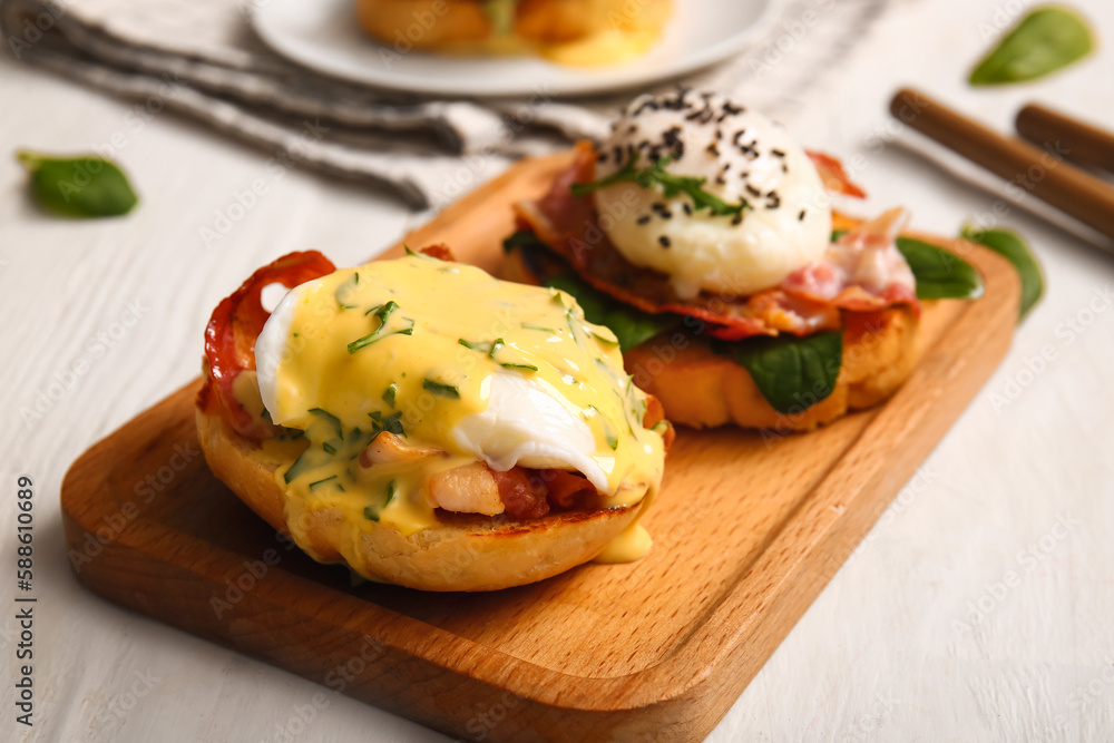 Board with delicious eggs Benedict on white wooden table, closeup