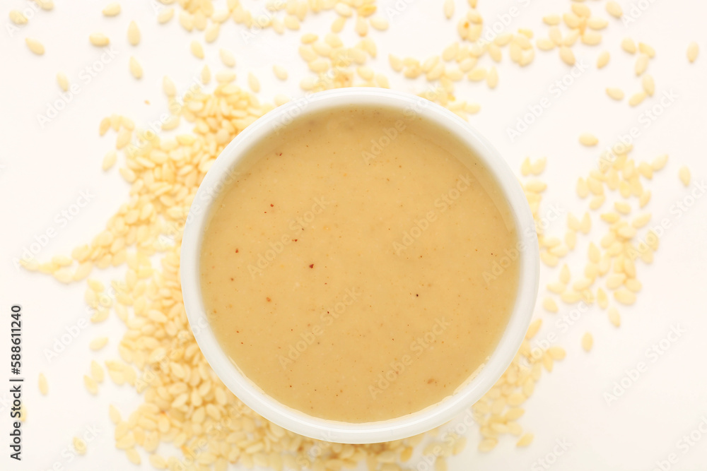 Bowl of tasty tahini and sesame seeds isolated on white background