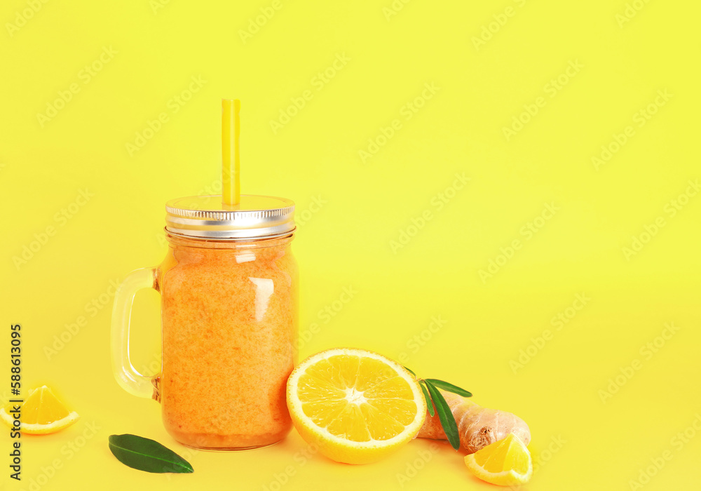 Mason jar of healthy orange smoothie with straw on yellow background