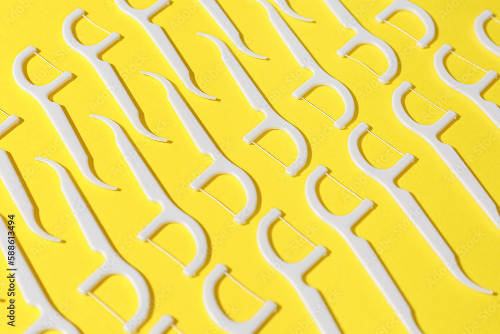 Many floss toothpicks on yellow background