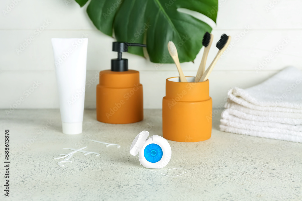 Case with dental floss and bath accessories on table, closeup