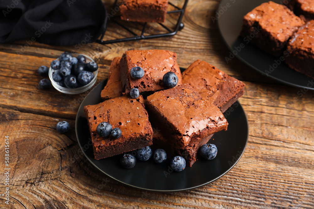 Plate with pieces of tasty chocolate brownie on wooden background