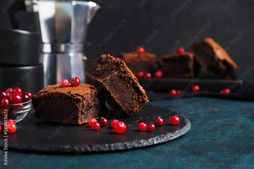 Board with pieces of tasty chocolate brownie on black background