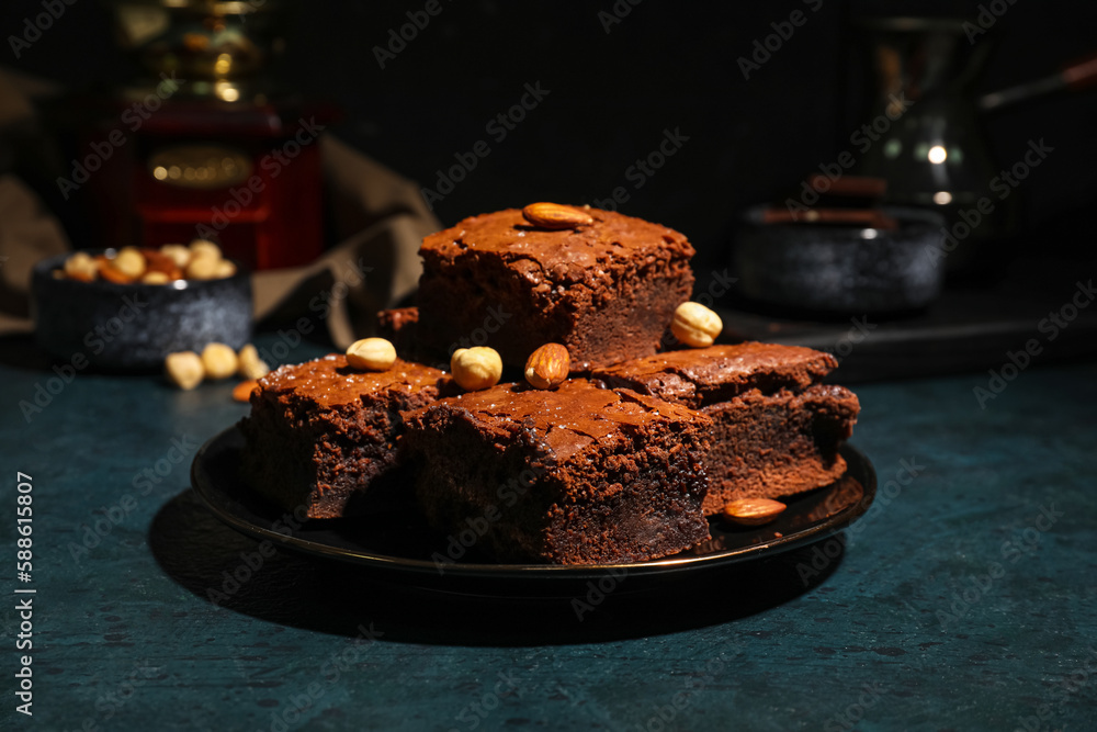 Plate with pieces of tasty chocolate brownie on black background